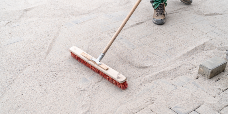 Landscaper adding sand to fill gaps in interlocking pavers - Filling in the Gaps: Transform Your Patio with These Paver Joint Fillers